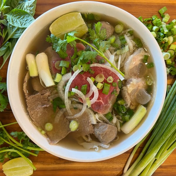 A bowl of Pho Dublin's Vietnamese pho with beef, noodles, lime, and fresh herbs.